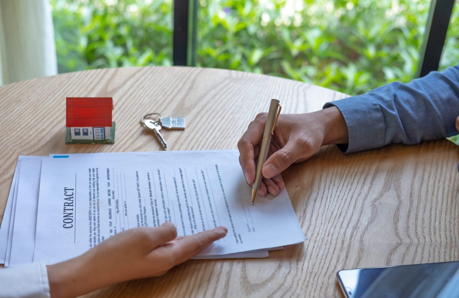Women Real Estate Agent showing where to sign on document for buy house contract, hand of man is signing a contract.